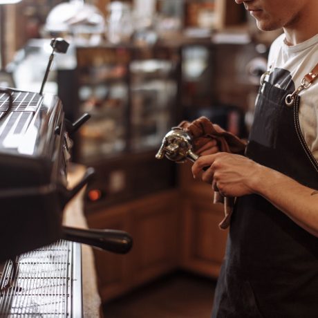 waiter is drying the coffee grinder after washing. side view cropped photo